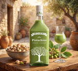 Pechery Pistazienlikör. Grüne Flasche mit Baum-Logo auf Holztisch neben gefülltem Glas und Schale mit Pistazien.