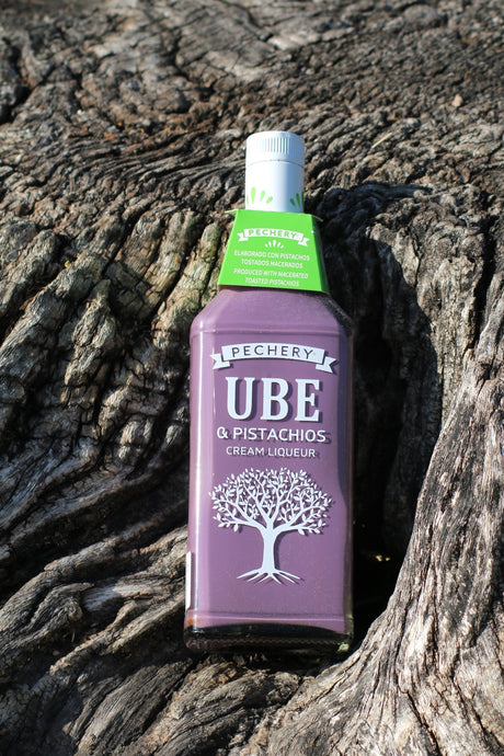 Pechery Ube & Pistachios Cream Liqueur Flasche auf Baumrinde mit violetter Flasche und grünem Halsetikett