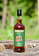 Bornholmer Sidevogn Bitter Dram Flasche auf Baumrinde vor grünem Hintergrund