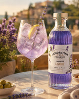 Spritz Lavande mit Lavendellikör Provence, Eis, Zitronenzeste und Lavendelzweig auf mediterraner Terrasse