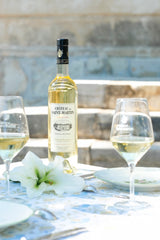 Château de St Martin Grande Réserve Blanc Weißwein mit zwei Gläsern auf gedecktem Tisch mit Blume und Geschirr
