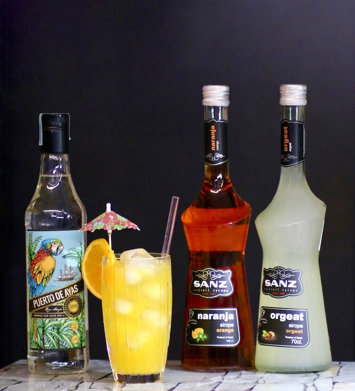 Sunshine Radiance Cocktail mit Rum, Orangensirup und Orgeat Sirup vor dunklem Hintergrund