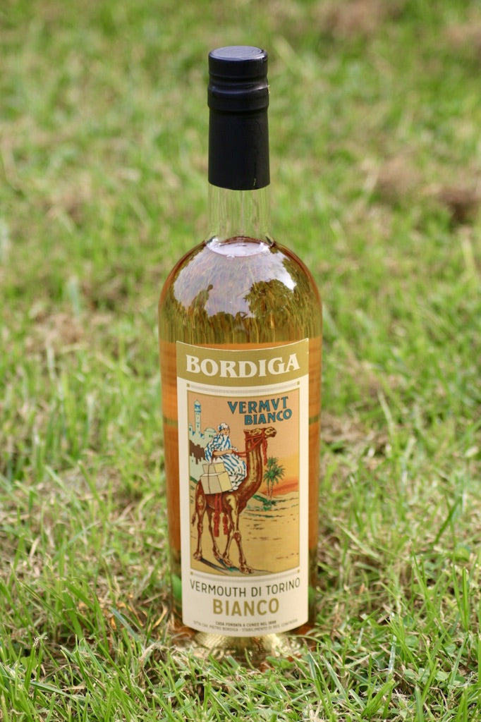 Flasche Bordiga Vermouth di Torino Bianco, 750 ml, mit schwarzem Verschluss und Vintage-Etikett, auf einer Wiese platziert.