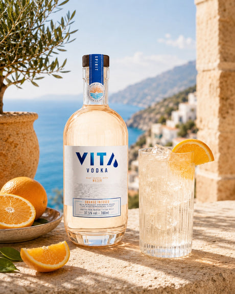 Vita Orange Wodka Flasche mit Longdrink, Orangenscheiben und mediterraner Küstenkulisse